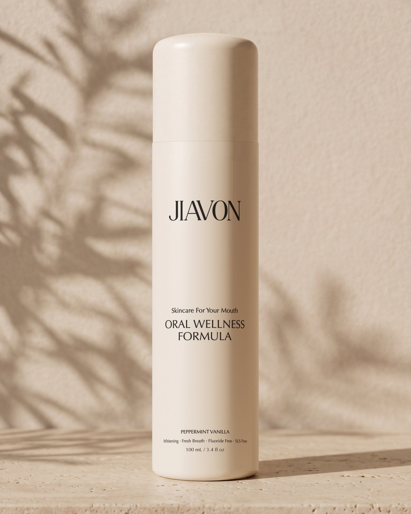 The JIAVON bottle on a travertine shelf with the shadow of an olive branch on a warm plaster wall